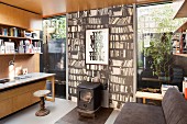 Home office with log burner against photo mural of bookcase in modern extension with floor-to-ceiling windows