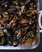 Baked mussels in a roasting tin with tomatoes, garlic and herbs