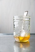 Honey in preserving jar with a spoon on a metal tray
