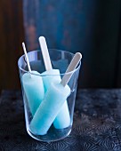 Three blue ice lollies in a glass
