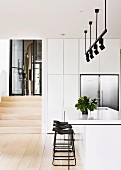 White kitchen island and bar stool under light rail with black spotlights in open kitchen