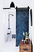 Bathroom with blue vintage door leaf as sliding element and rain shower