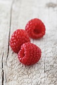Three raspberries on a wooden surface