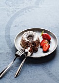 Warm chocolate cake with a liquid core dusted with icing sugar and served with strawberries
