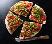 Bruschetta pizza with a knife on a black baking tray