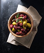 Kalamata olives and green olives in a wooden bowl on a linen napkin
