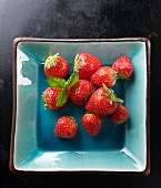 Fresh strawberries with leaves in a ceramic bowl