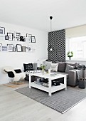 Schwarz-weiße Wohnzimmerecke mit Holztisch, grauer Polstercouch und gerahmten Botschaften