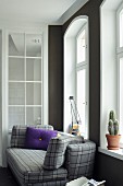 Kariertes Sofa mit violettem Kissen vor Bogenfenstern
