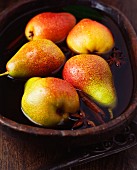 Pears with cinnamon sticks and star anise in a bowl of water