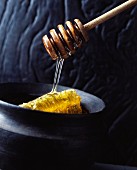 Honey flowing from a spoon onto a honeycomb