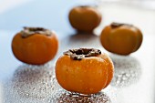 Four persimmons sprayed with water drops