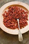 Goji berries on a wooden plate with a spoon