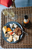 A cheese platter and champagne on a wicker table