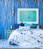 Double bed with patterned bed linen in front of a blue partition