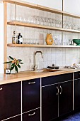 Kitchenette with black fronts and shelves on wall with glasses