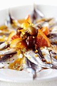 Anchovies in an orange marinade with pink pepper and olives