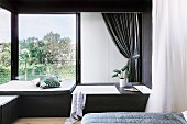 Elegant bedroom corner with built-in bathtub in front of window