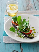 An open aubergine sandwich topped with pepper and feta cheese
