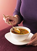 Frau eine indische Linsen-Tomaten-Suppe essend