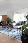 Modern coffee table and retro leather armchair in front of sofa below window in rustic living room