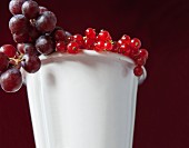 Redcurrants and grapes in a white enamel cup