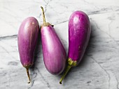 Three aubergines on a marble surface