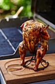 Grilled jerk chicken on a stand in front of a barbecue
