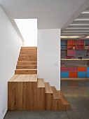 Wooden landing and staircase with view of colourful fitted kitchen to one side