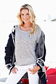 Junge blonde Frau in grau meliertem Strickshirt und Strickjacke