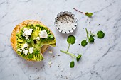 A bagel with avocado, ricotta, watercress, salt and pepper