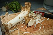 A peeled horseradish root on a wooden chopping board