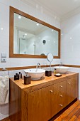 Badezimmer mit massgefertigtem Waschtisch aus Holz vor gerahmtem Wandspiegel