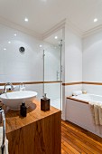 Edelholz-Waschtisch mit weißem Aufsatzbecken gegenüber Badewanne und Duschbereich