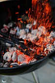 Glowing charcoal being stirred in a barbecue