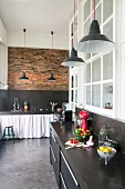 Black kitchen counters in loft apartment with brick wall and polished concrete floor