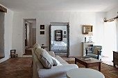 Helles Polstersofa und Armlehnstuhl um Couchtisch im Wohnzimmer mit Terrakottafliesenboden