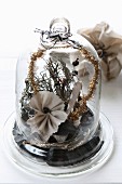 Christmas arrangement of fabric flowers and moss under glass cover