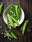 Fresh peas and pea pods on a wooden table