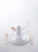 A white place setting with copper cutlery