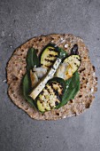 A wholemeal tortilla topped with grilled vegetables and cheese