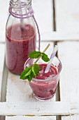 A glass of berry smoothie garnished with mint