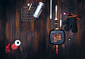 Barbecuing utensils and accessories on a dark wooden surface