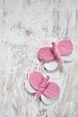 DIY-Schmetterlinge aus rosa und weißem Filz mit Kupferdraht umwickelt auf Vintage Holzuntergrund