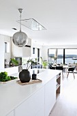 White island counter and spherical lamp in open-plan living area with view of countryside