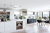 Dining area, black chairs and panoramic window in white, open-plan designer kitchen