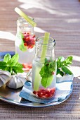 Lemon juice with pomegranate seeds and mint in bottles