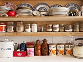 Küchenregal mit verschiedenen Tellerstapeln, Aufbewahrungsgläsern und Keramikgefäßen