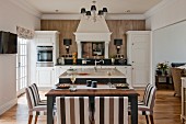 Island counter and set dining table in white, open-plan, country-house kitchen