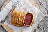 Beef Wellington, sliced, on a piece of paper (seen from above)